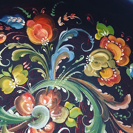 Inside of a small wooden bowl with colourful handpainted rosemaling in Telemark style on a dark background