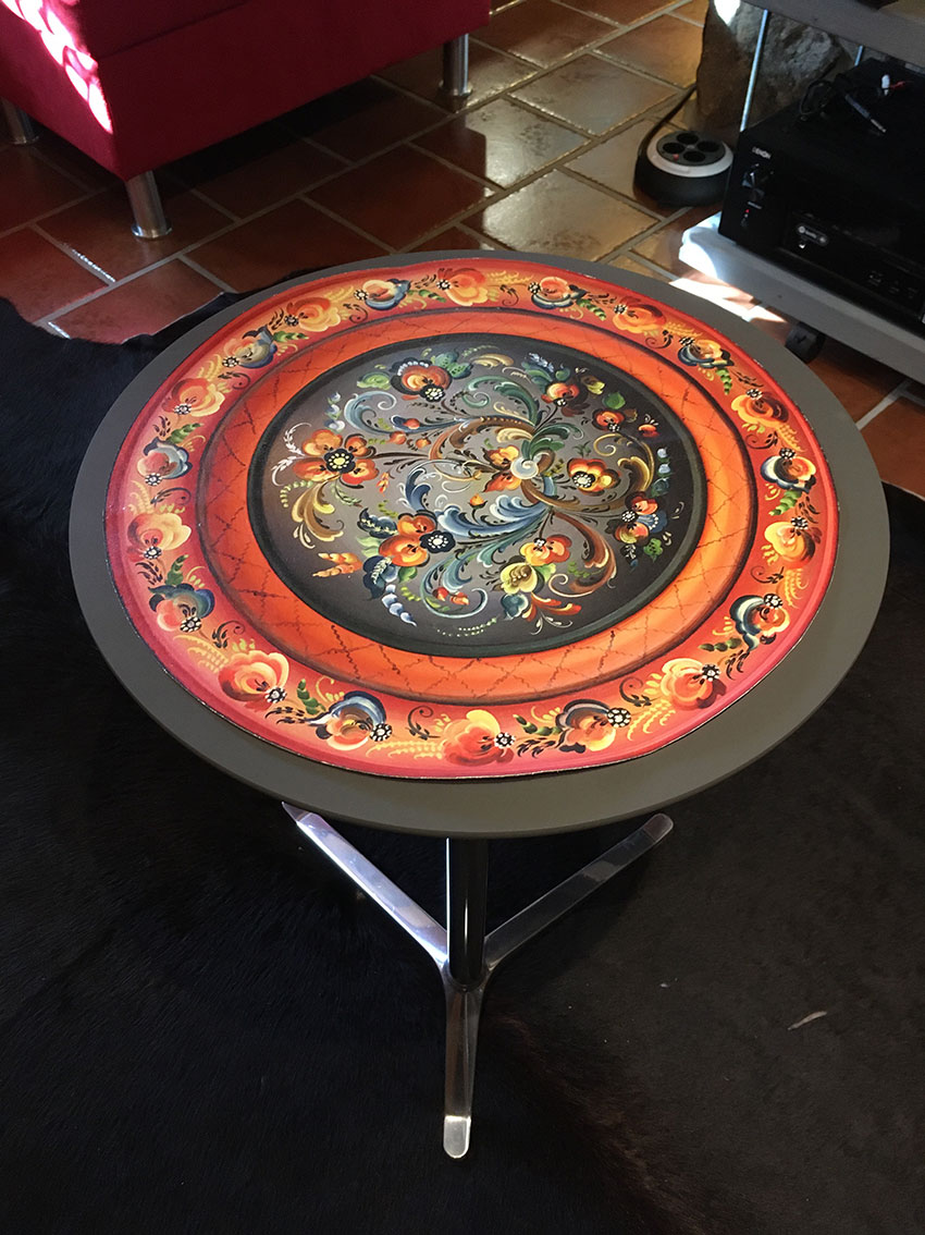 A circular table mat of canvas with Norwegian rosemaling decoration
